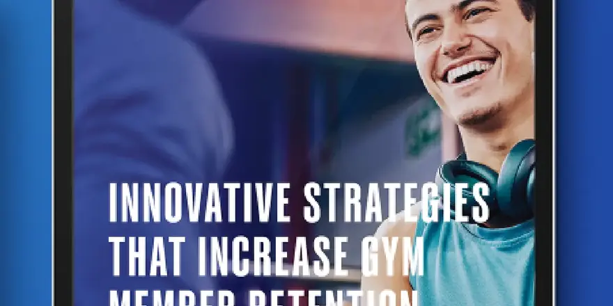 A smiling man in athletic wear with headphones around his neck stands next to gym equipment. Text on the tablet screen reads, Innovative Strategies That Increase Gym Member Retention.
