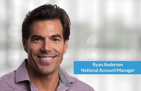 Smiling man with dark hair wearing a red and white checkered shirt, standing in front of a blurred background. Text on image reads, Ryan Andersen, National Account Manager.
