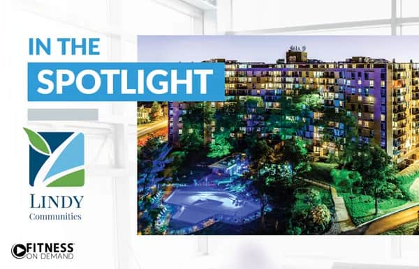 A brightly lit apartment building at night is featured with the text IN THE SPOTLIGHT and logos for Lindy Communities and Fitness On Demand on the left side.