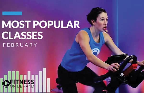 A woman wearing a headset is riding a stationary bike in a fitness studio. The text reads Most Popular Classes February. At the bottom left, a Fitness On Demand logo appears with vertical bar graphics.