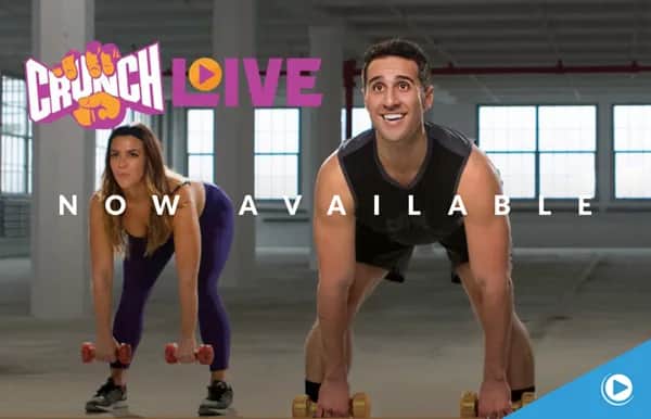 Two people in workout clothes lift dumbbells in a gym. The text reads CRUNCH LIVE and NOW AVAILABLE. A small play button icon appears in the bottom right corner.