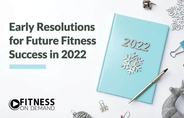 A blue 2022 planner with a snowflake decoration and a pen lies on a white surface among holiday ornaments. Text reads “Early Resolutions for Future Fitness Success in 2022.” Fitness On Demand logo appears bottom left.