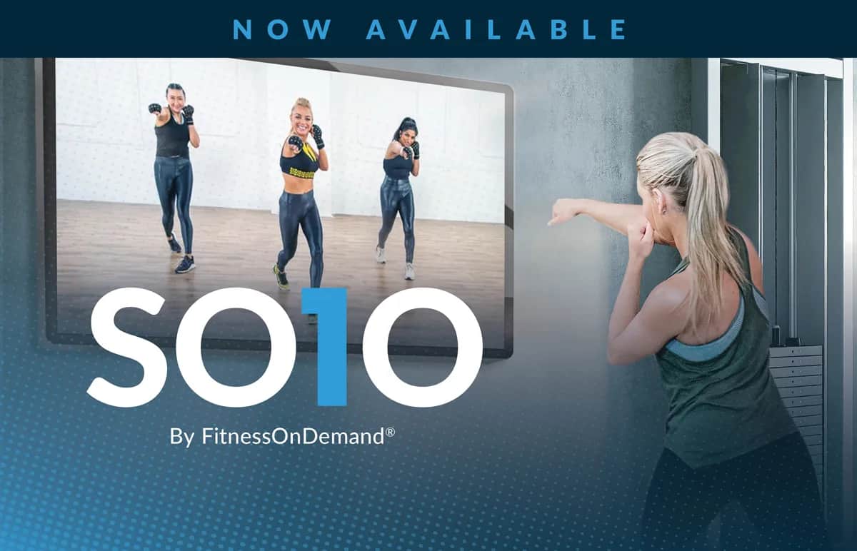 A woman follows a virtual boxing workout on a screen, mirroring three instructors. Text reads NOW AVAILABLE and SOLO By FitnessOnDemand®.