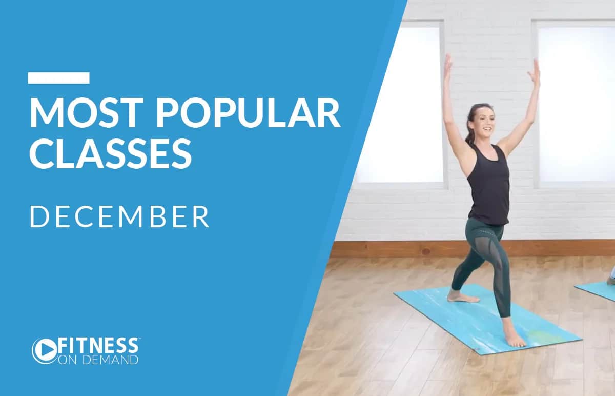 A woman practices yoga on a blue mat in a bright room. Text on a blue overlay reads Most Popular Classes December with the Fitness On Demand logo in the corner.