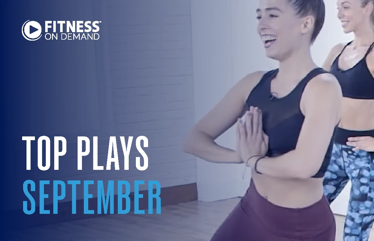 Two women in workout attire exercise indoors, smiling, as text reads Fitness On Demand Top Plays September on a blue gradient background.