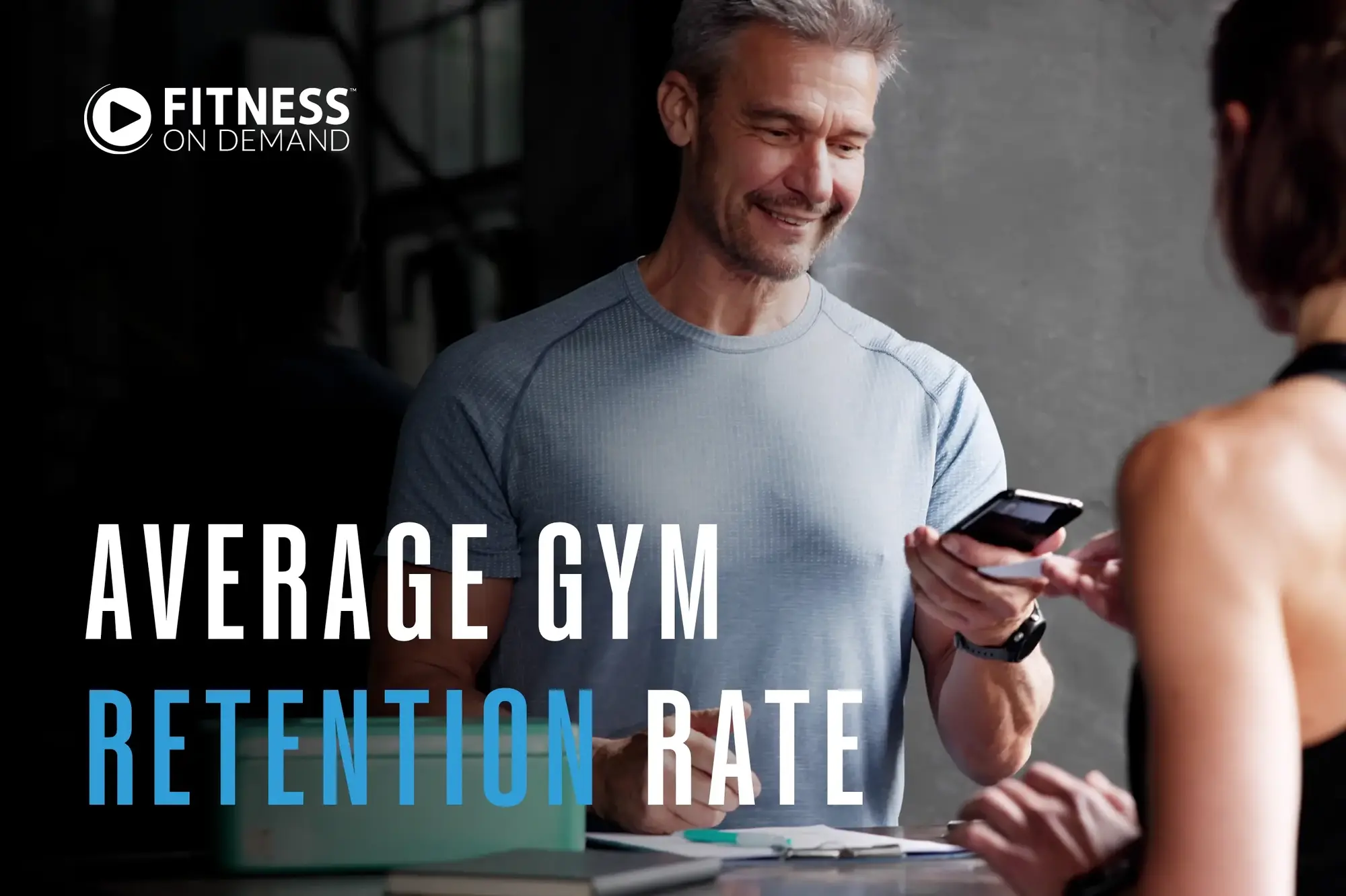 A smiling man in a gym checks his phone while talking to a woman. Text on the image reads: Average Gym Retention Rate. The Fitness On Demand logo appears in the upper left corner.