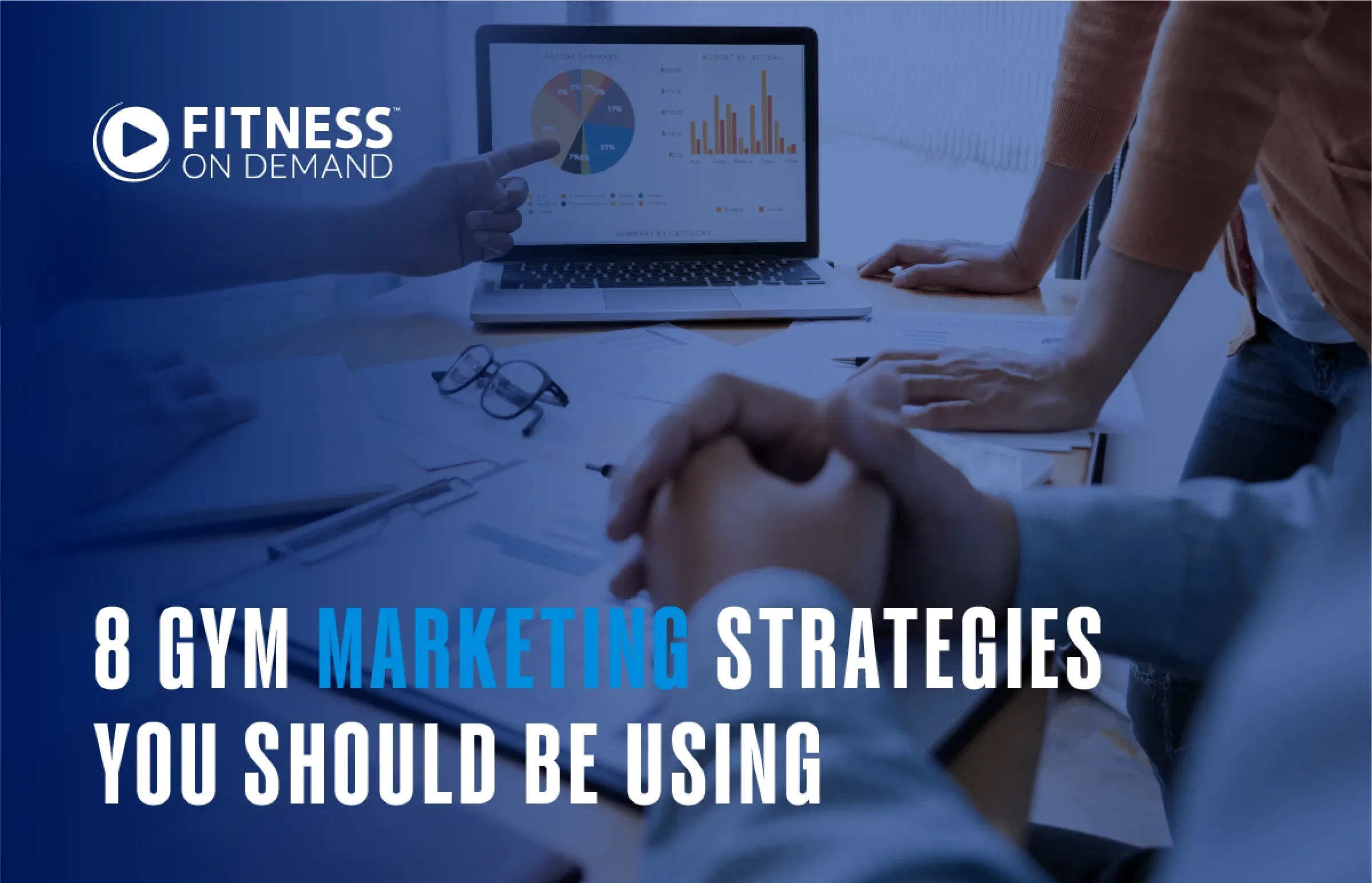 A group of people in a meeting discuss marketing strategies at a table with a laptop displaying graphs. Text reads: 8 Gym Marketing Strategies You Should Be Using. Fitness On Demand logo is in the corner.