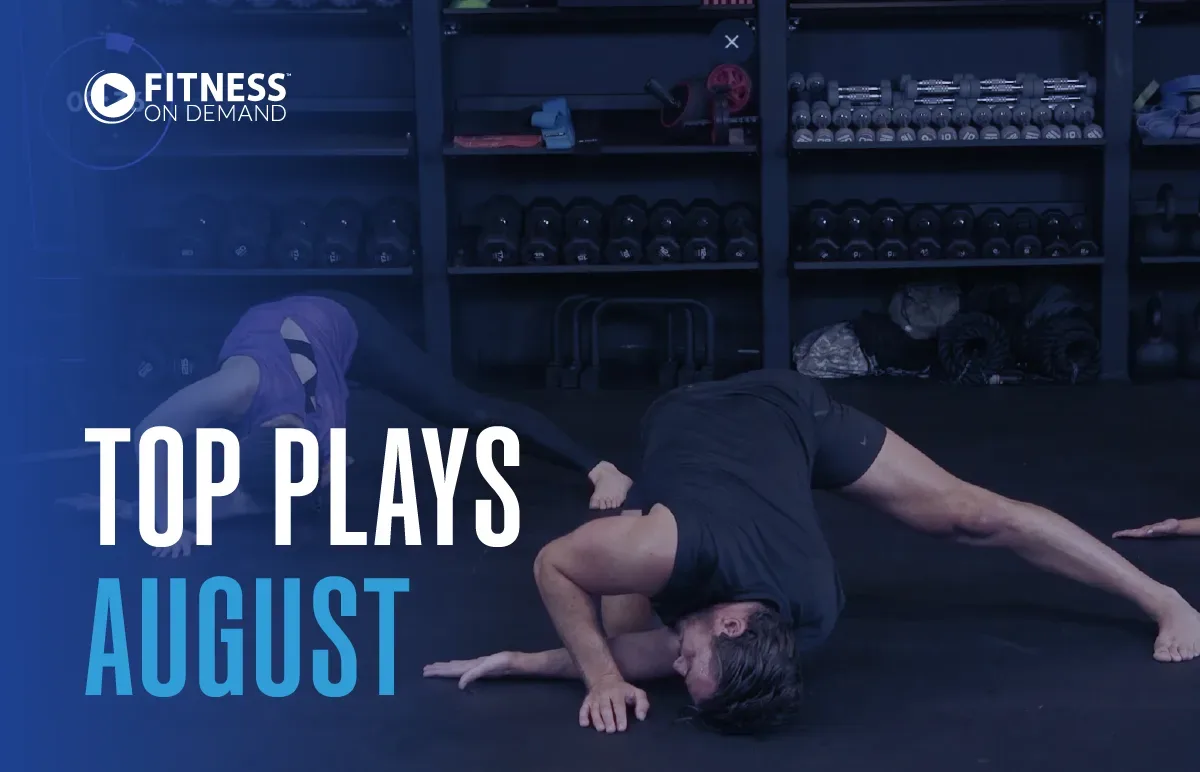 Two people stretch on a gym floor in front of shelves with fitness equipment. Text reads Fitness On Demand. Top Plays August. The image has a blue overlay on the left side.